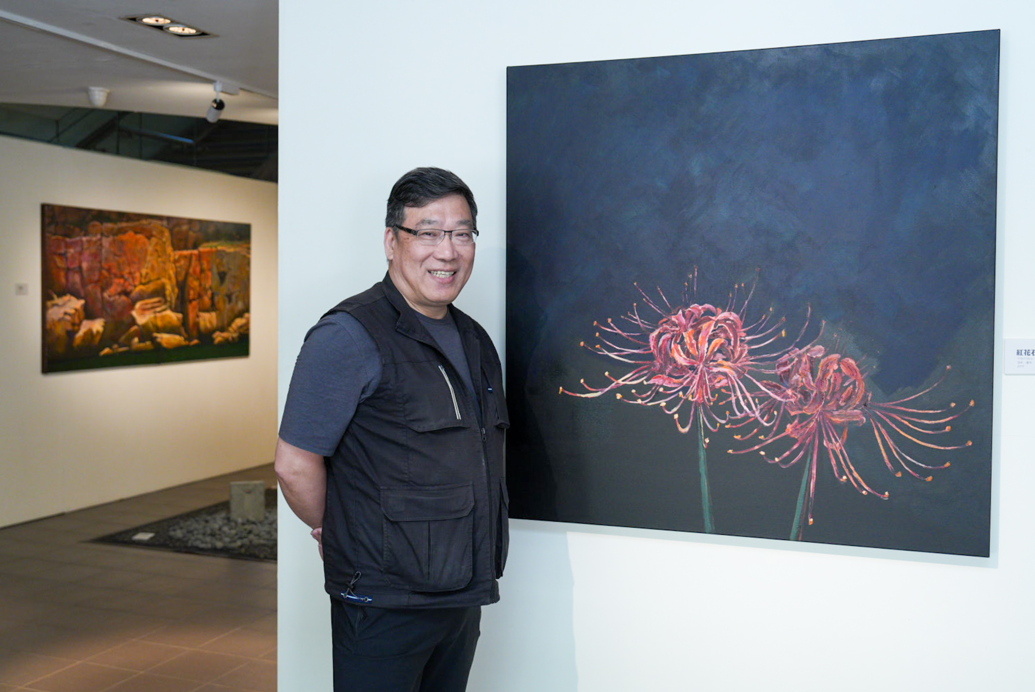 中原大學舉辦《馬祖‧藍眼淚》個展，藝術家曹松清於畫作＜紅花石蒜＞前留影。