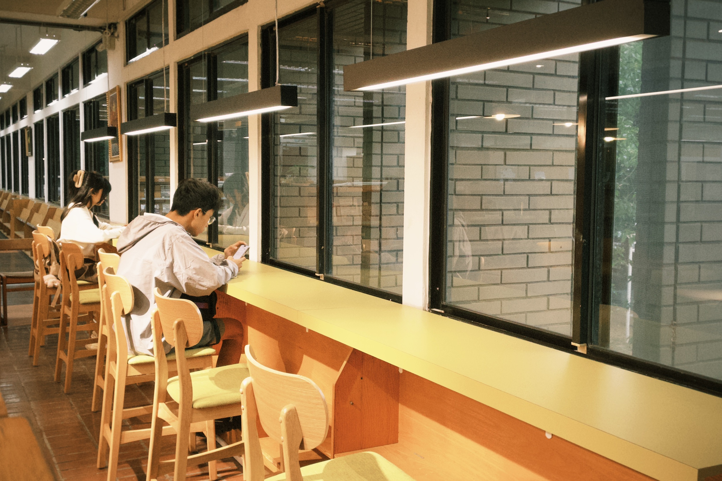 將老舊期刊架再生打造窗邊閱讀桌，讓讀者在陽光與綠意環抱中享受靜謐閱讀時光。