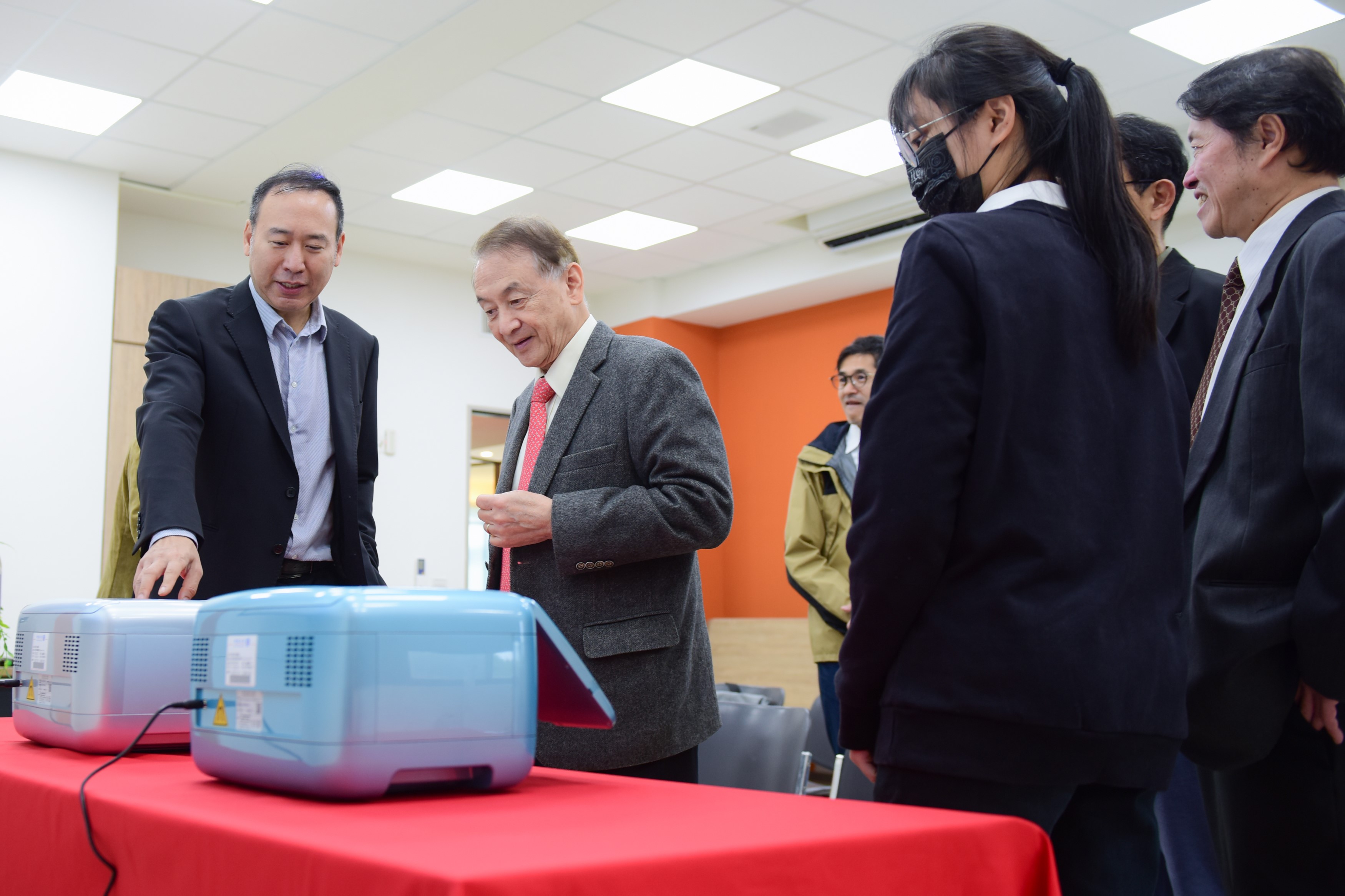 育秀教育基金會副執行長苗華斌(左1)與中原大學董事長張光正(左2)等人圍觀量子電腦。