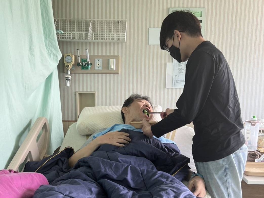 王明誠老師因病無法自理，學生細心餵食，照顧無微不至。