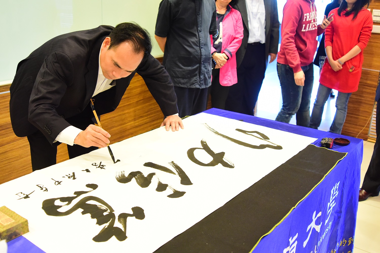 曾祥輝以大筆書寫中原大學校訓「篤信力行」四大字，送給校方作為紀念