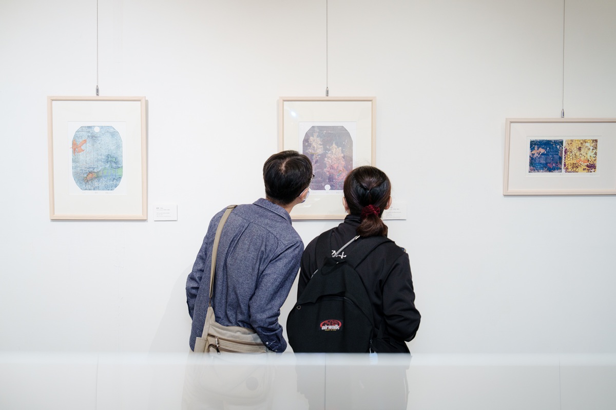 參觀者在展場上，近距離欣賞版畫細緻層次。