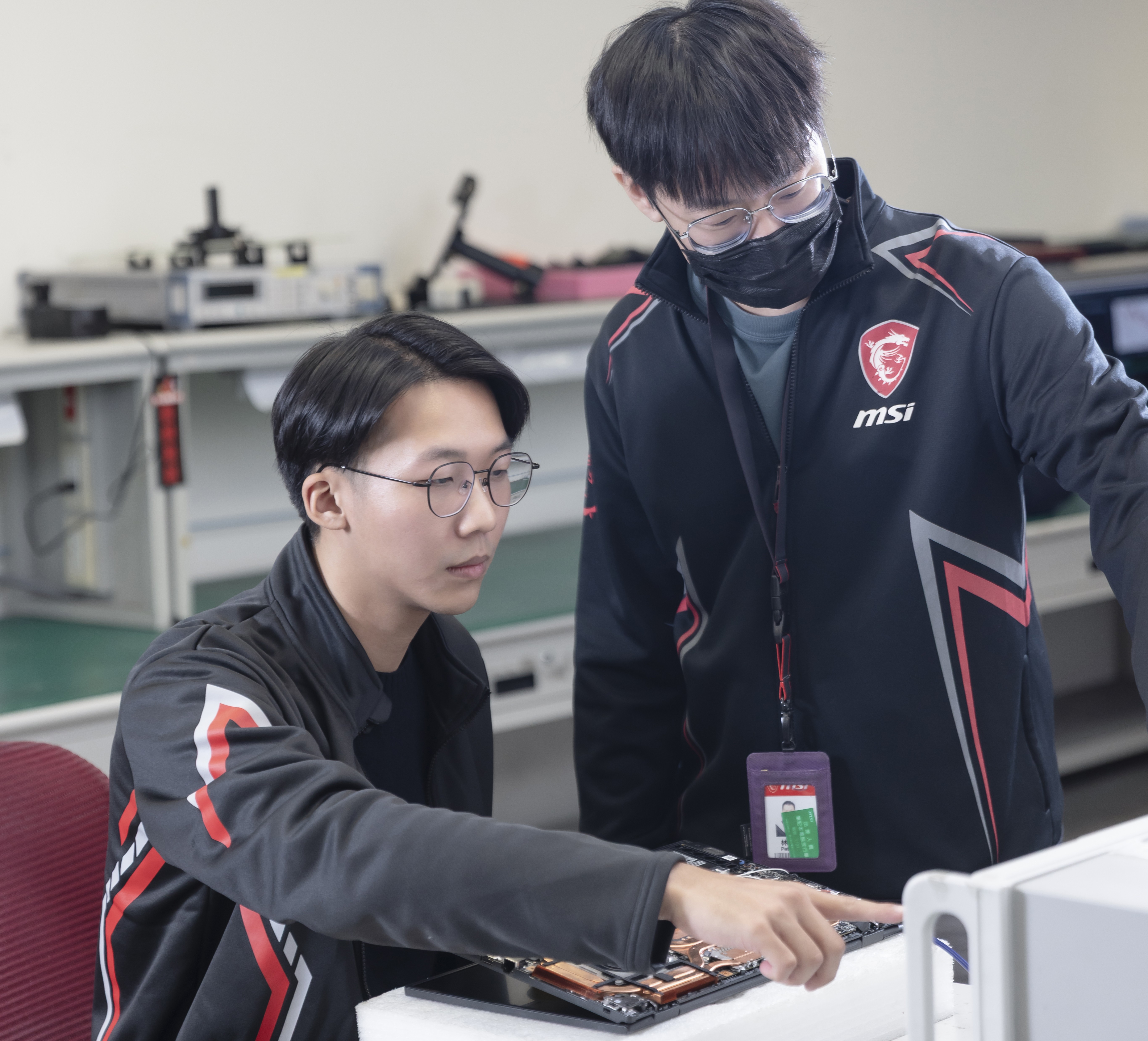 許朝欽同學(左)檢視主機板電路並進行訊號量測。